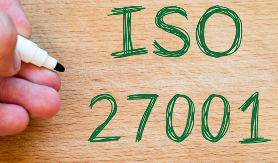 ISO 27001 met groene stift geschreven op een houten ondergrond