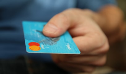 Een close-up van een hand dat een blauwe bankkaart vasthoudt