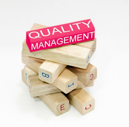 Blocs de bois dont l'un est rose et porte l'inscription 'quality management'