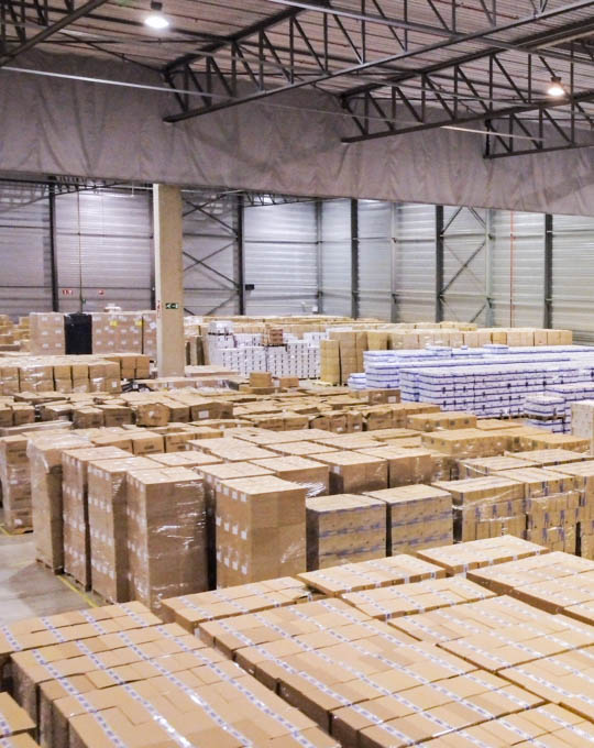 Een afbeelding van een opslagruimte met talrijke dozen op elkaar gestapeld, waarbij een goed georganiseerde opslagfaciliteit wordt geïllustreerd.