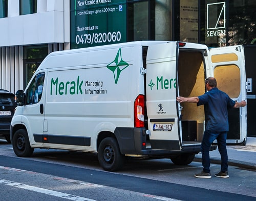 Koerier van Merak die de deuren sluit van zijn bestelwagen