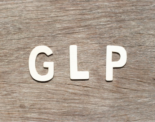 White letters spelling GLP on a wooden background