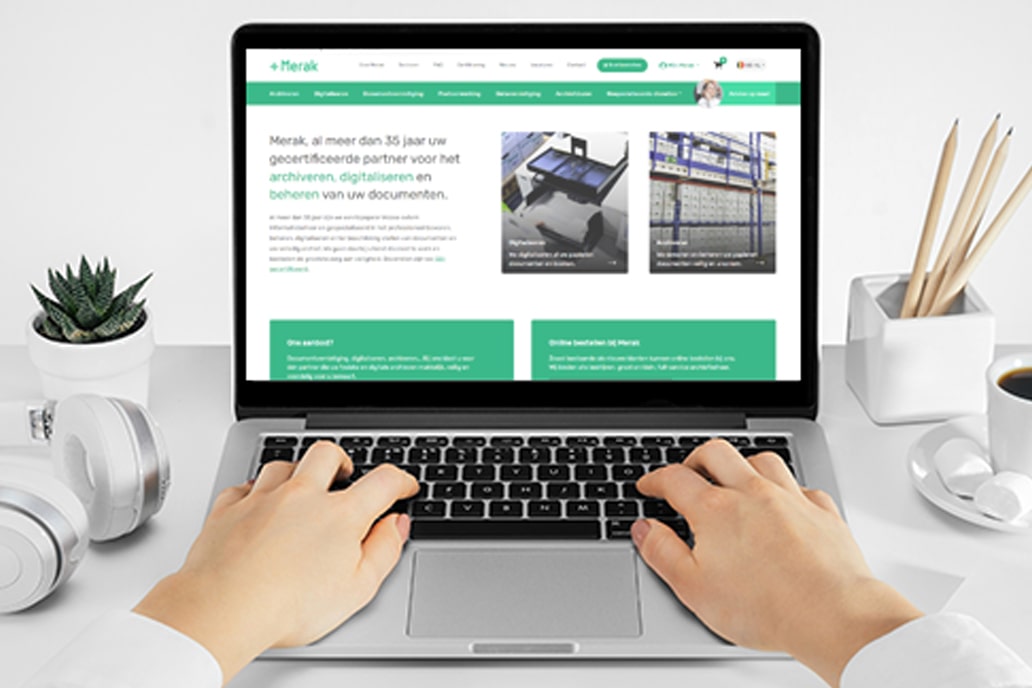 Mains tapant sur un ordinateur portable avec le site web de Merak ouvert montrant des services d'archivage et de numérisation.