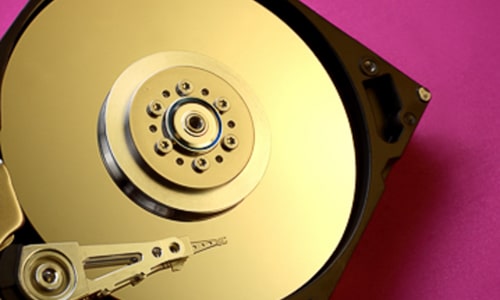A gold hard drive on a pink background