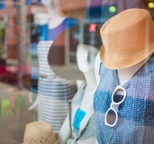 Een close-up van een vitrine van een kledingwinkel met die zomers geklede paspoppen