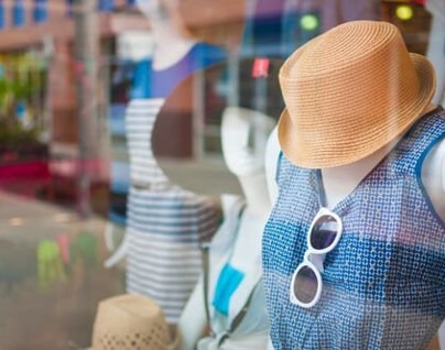 Close-up of a display case of a clothing shop with three summer-dressed mannequins