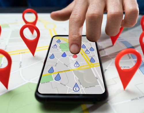 Une personne tient un smartphone avec une carte GPS à l'écran. Vous pouvez trouver des emplacements Merak à Anvers, Bruxelles, Malines et Hoogstraten.