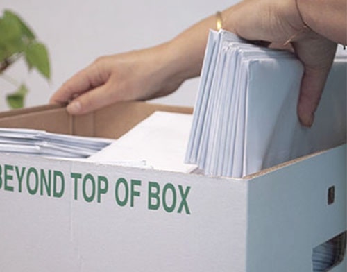 Close-up of someone filling an archive box with documents