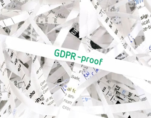 A pile of paper scraps on which the word GDPR is written in green letters