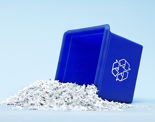 A blue plastic box lies on its side and shreds of paper fall out