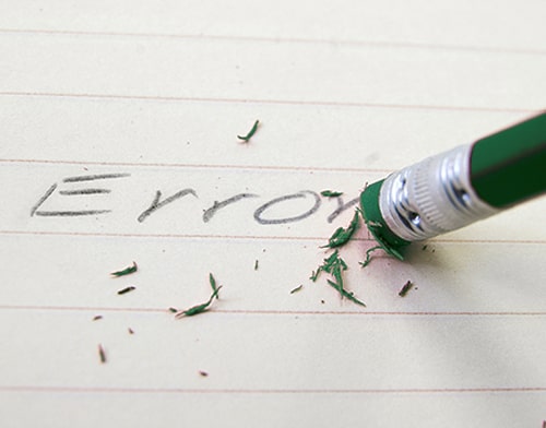 Een groen potlood gomt het woord error weg van op een papier